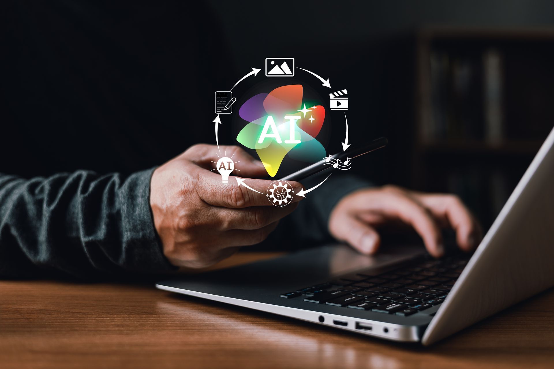 Person using a laptop, holding a phone with an 