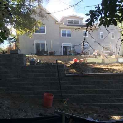A large house is being built next to a brick wall.