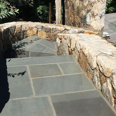 A stone walkway with stairs leading up to a stone wall.