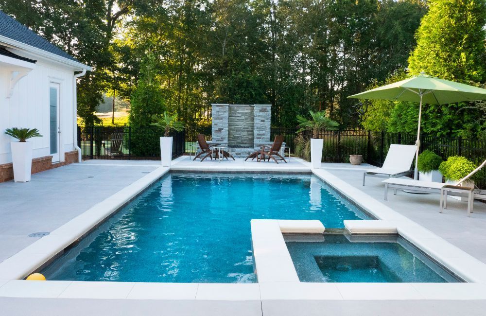 A large swimming pool surrounded by chairs and umbrellas in a backyard.