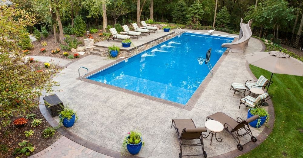 An expansive backyard with a pool, lounge chairs, and a slide.