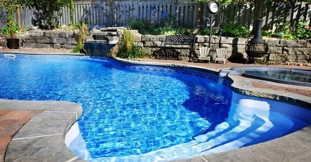 A residential backyard with a pool and a waterfall.