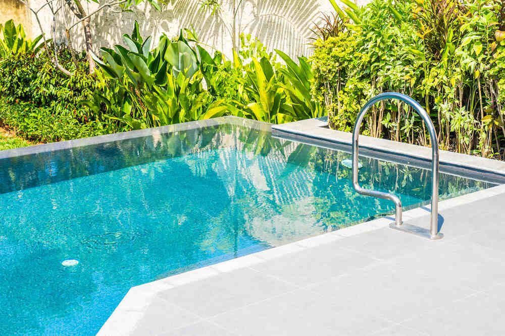 A large swimming pool with a staircase leading to it surrounded by trees.