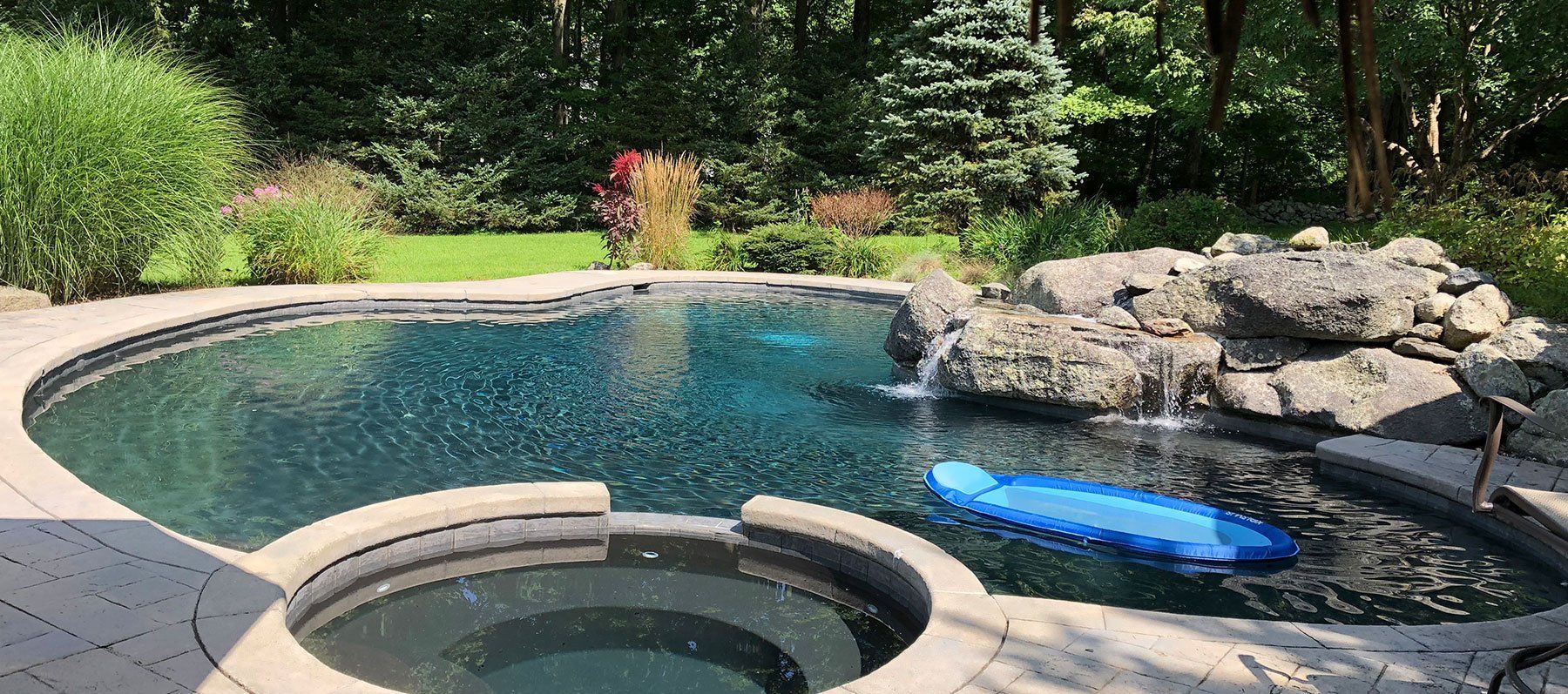 A large swimming pool with a hot tub in the middle of it.