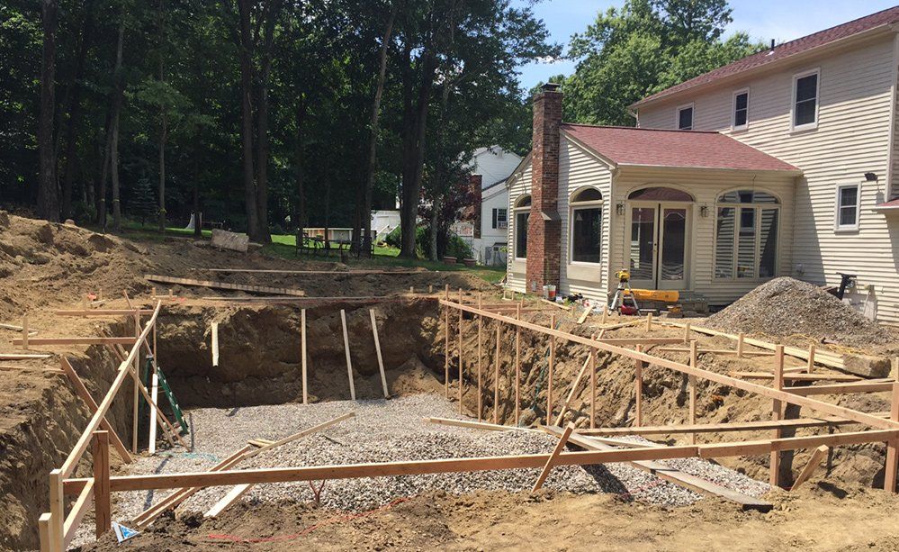 A swimming pool is being built in the backyard of a house.