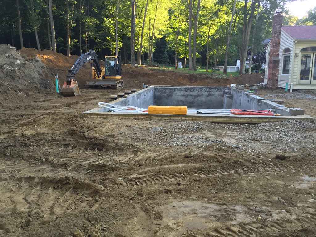 A swimming pool is being built in the backyard of a house.