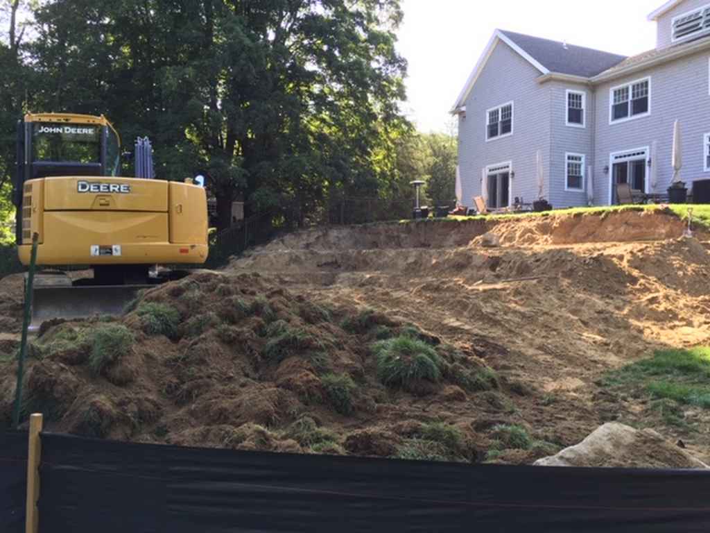 A large pile of dirt is in front of a large house.