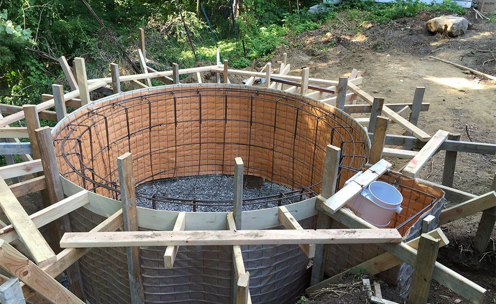 A large circular structure is being built with wooden beams and bricks.