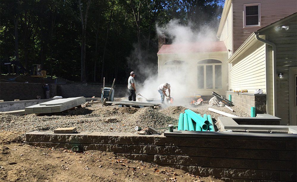 A construction site with smoke coming out of it and a house in the background