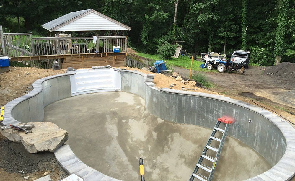 A large swimming pool is being built in the backyard of a house.