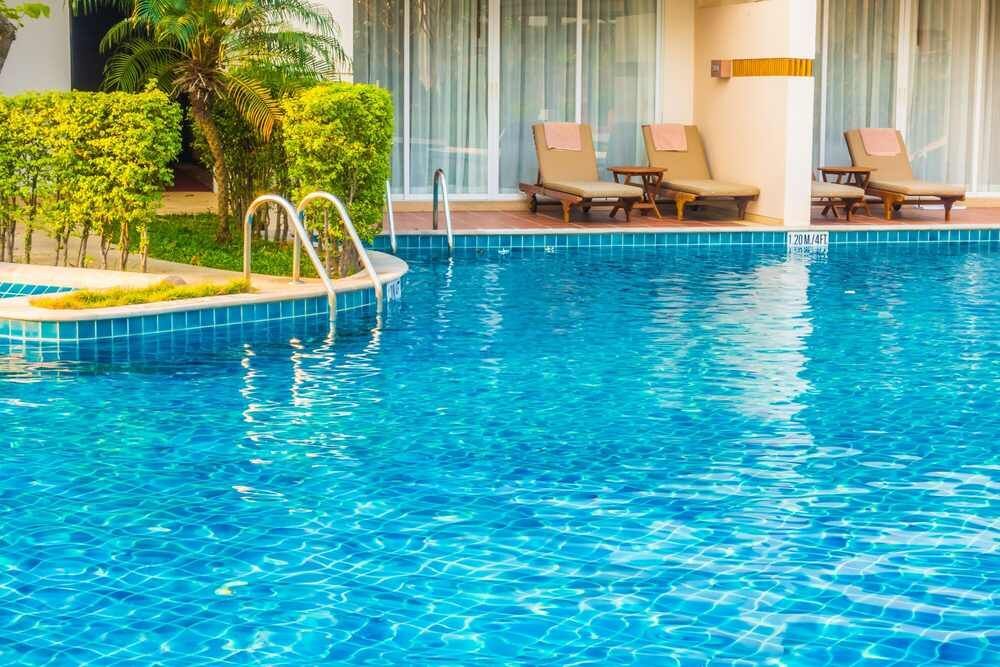 A large swimming pool surrounded by chairs and a staircase.