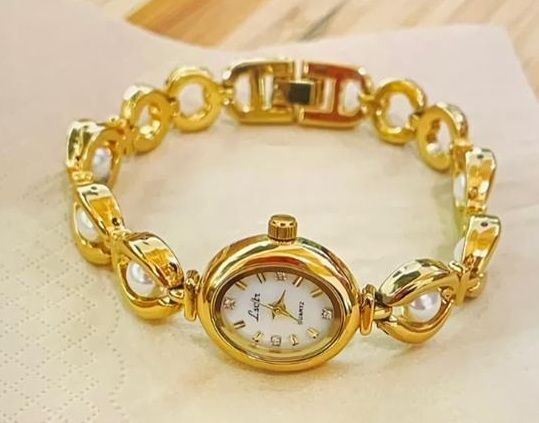 Een gouden armband met een horloge eraan
