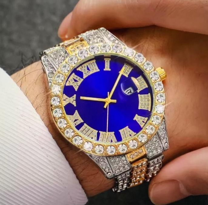 Een persoon draagt een horloge met een blauwe wijzerplaat en Romeinse cijfers