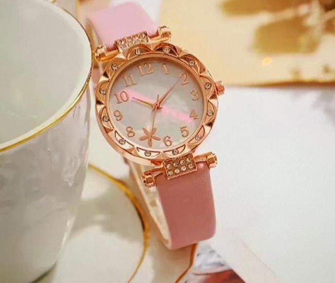 Een roze horloge ligt op een schoteltje naast een kopje