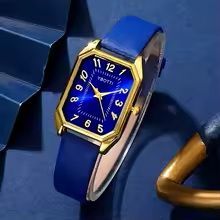 Een blauw en gouden horloge ligt op een blauw oppervlak.