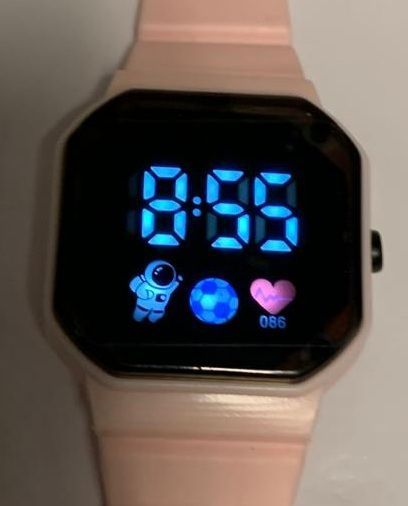 Een digitaal horloge met een roze band geeft de tijd aan als 8:36