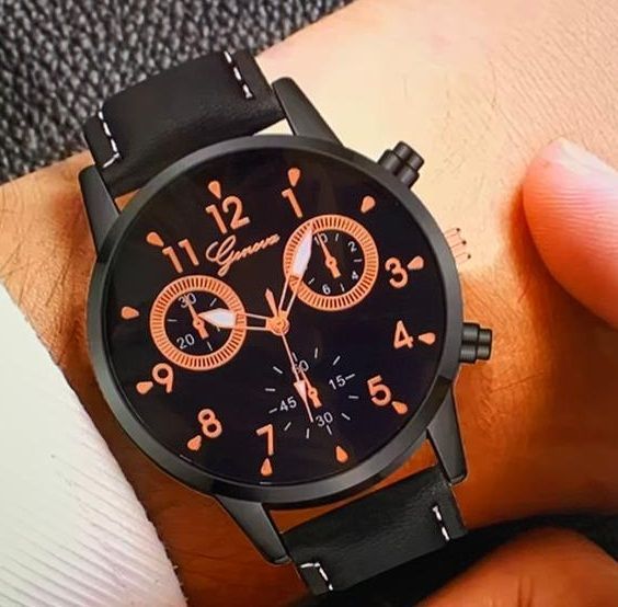 Een persoon draagt een zwart Genève horloge om zijn pols