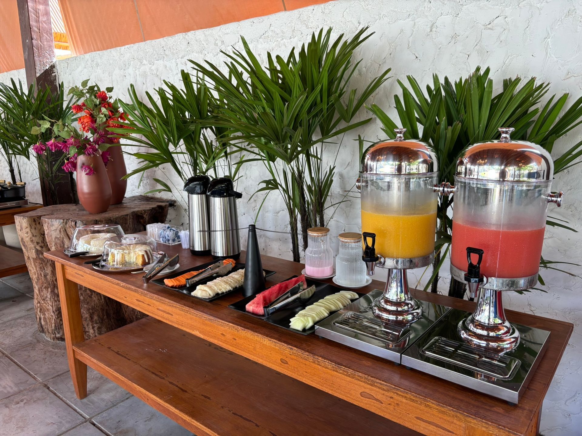 Uma mesa de madeira coberta com uma variedade de comidas e bebidas. Coralli Pousada