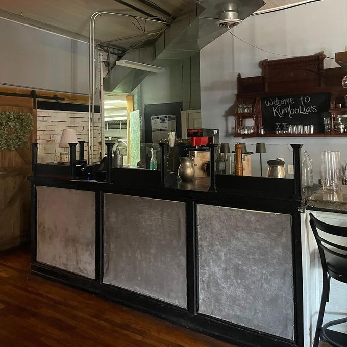 A coffee bar with a black and silver facade, wood paneling, and the words 
