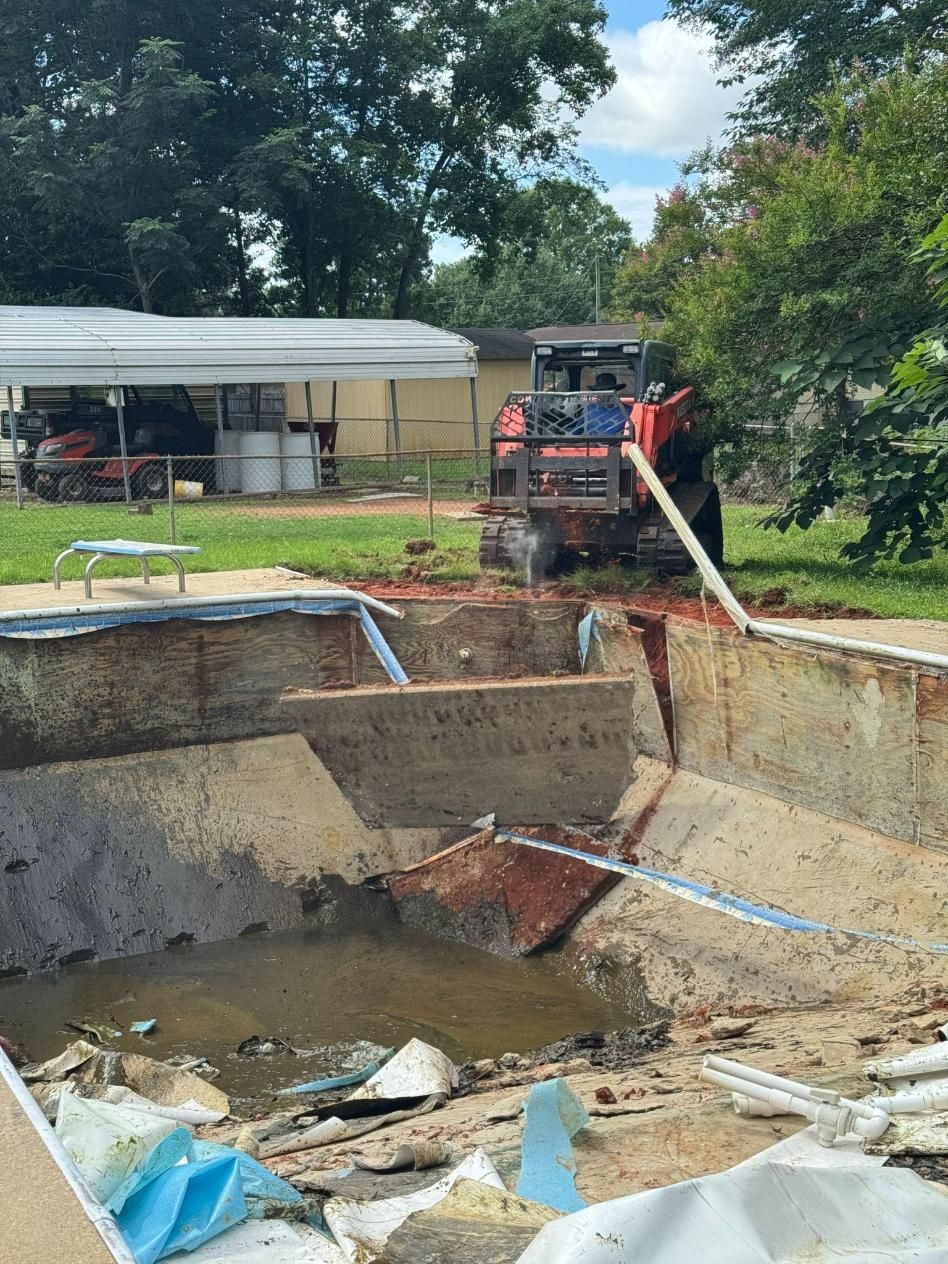 Excavator removing concrete pool, backyard setting. Debris and water visible.