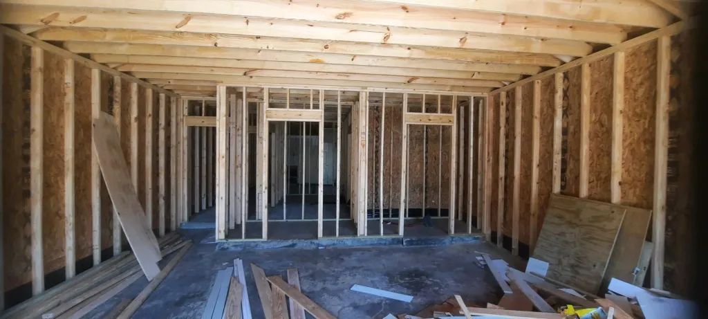 Interior of a building under construction, showing wooden framing for walls, doorways, and ceiling.