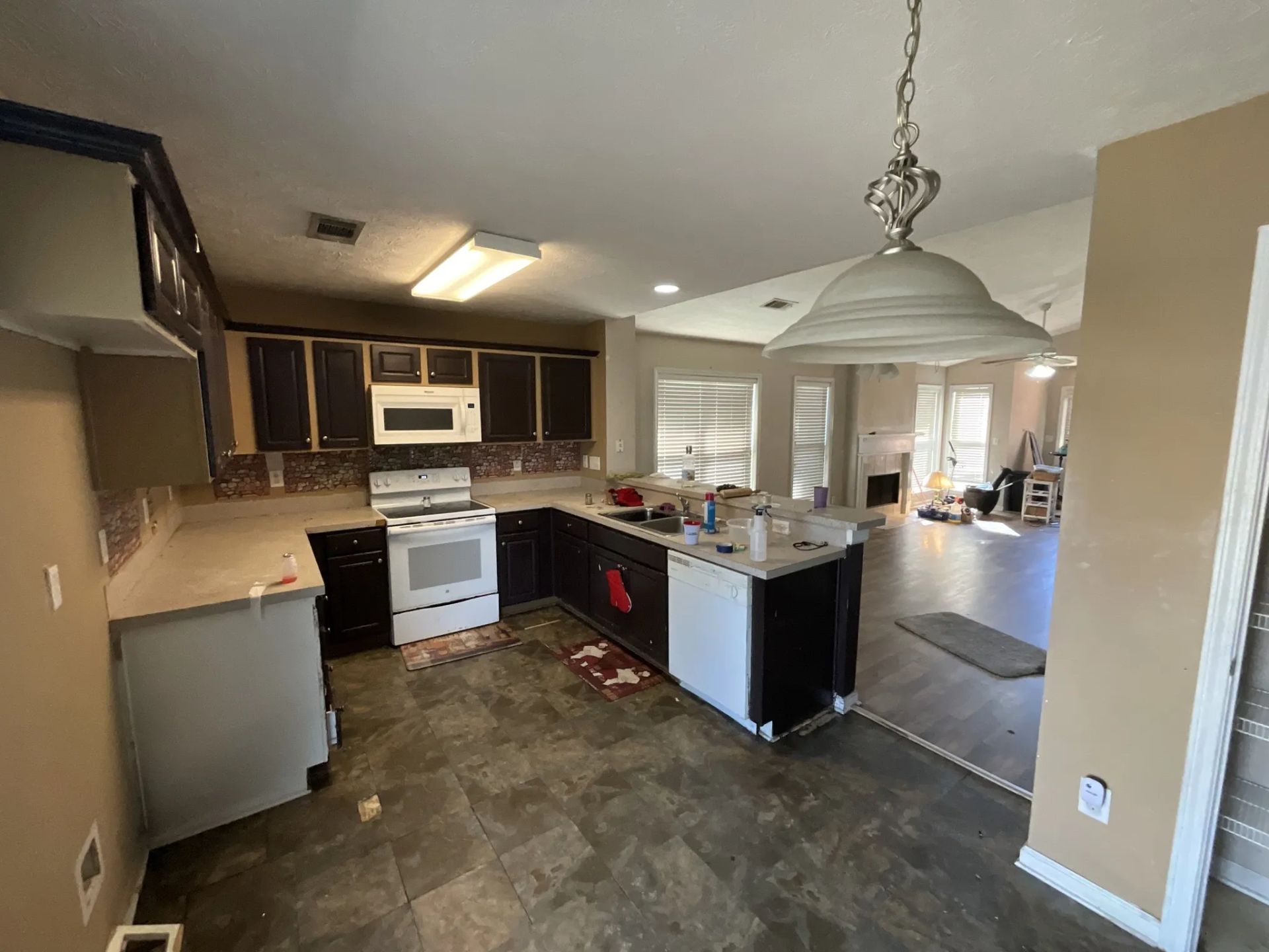 Kitchen with dark cabinets, white appliances, and a connected living area.