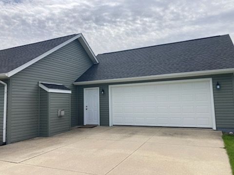 A house with a garage and a driveway in front of it.