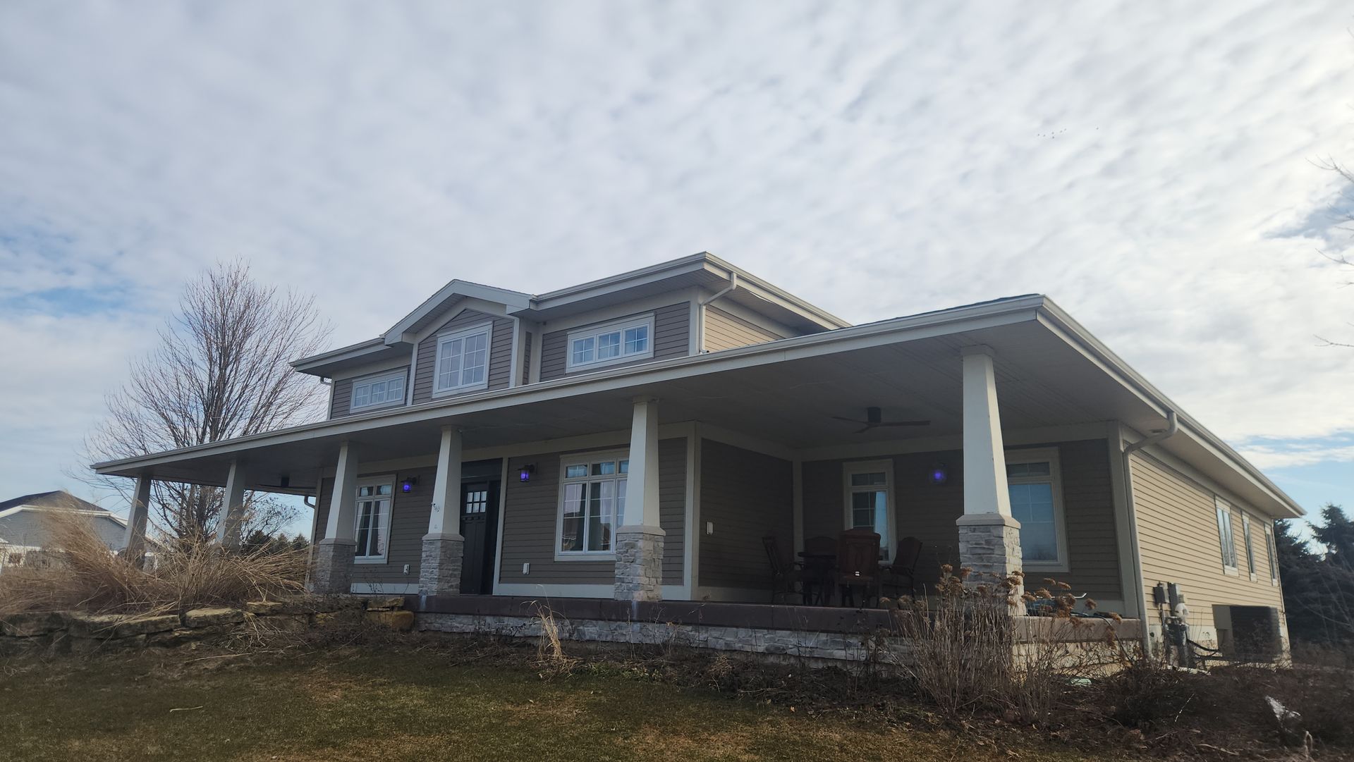 A large house with a new siding and a large porch with a lot of windows