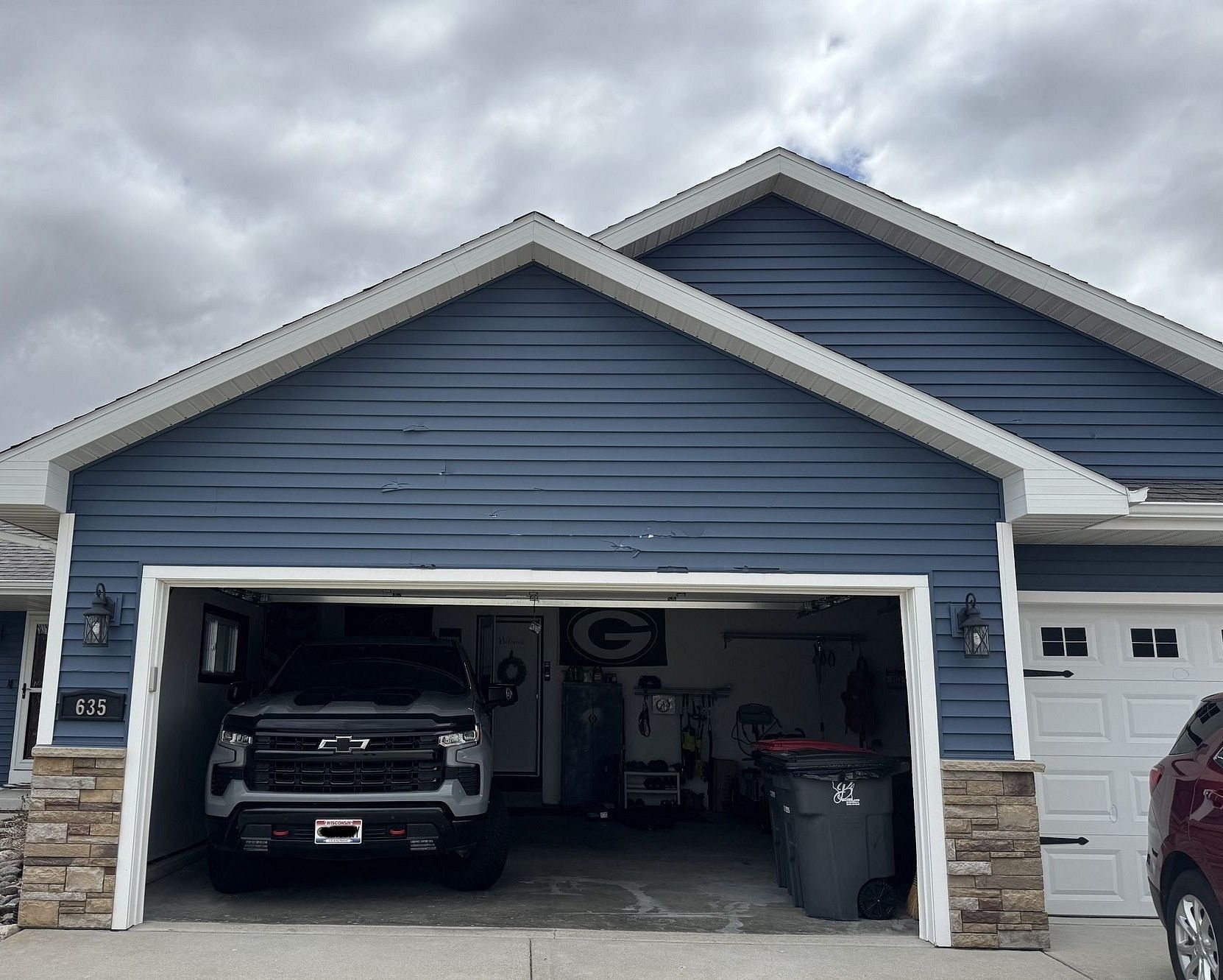 The back of a house with a grill in the backyard on a cloudy day.