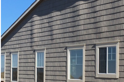 A row of windows on the side of a house with buckling siding