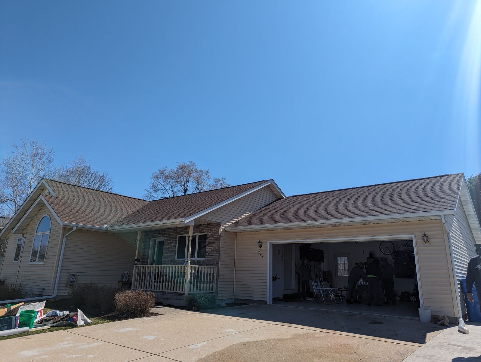 A house with a brown roof and a garage with a blue sky in the background.