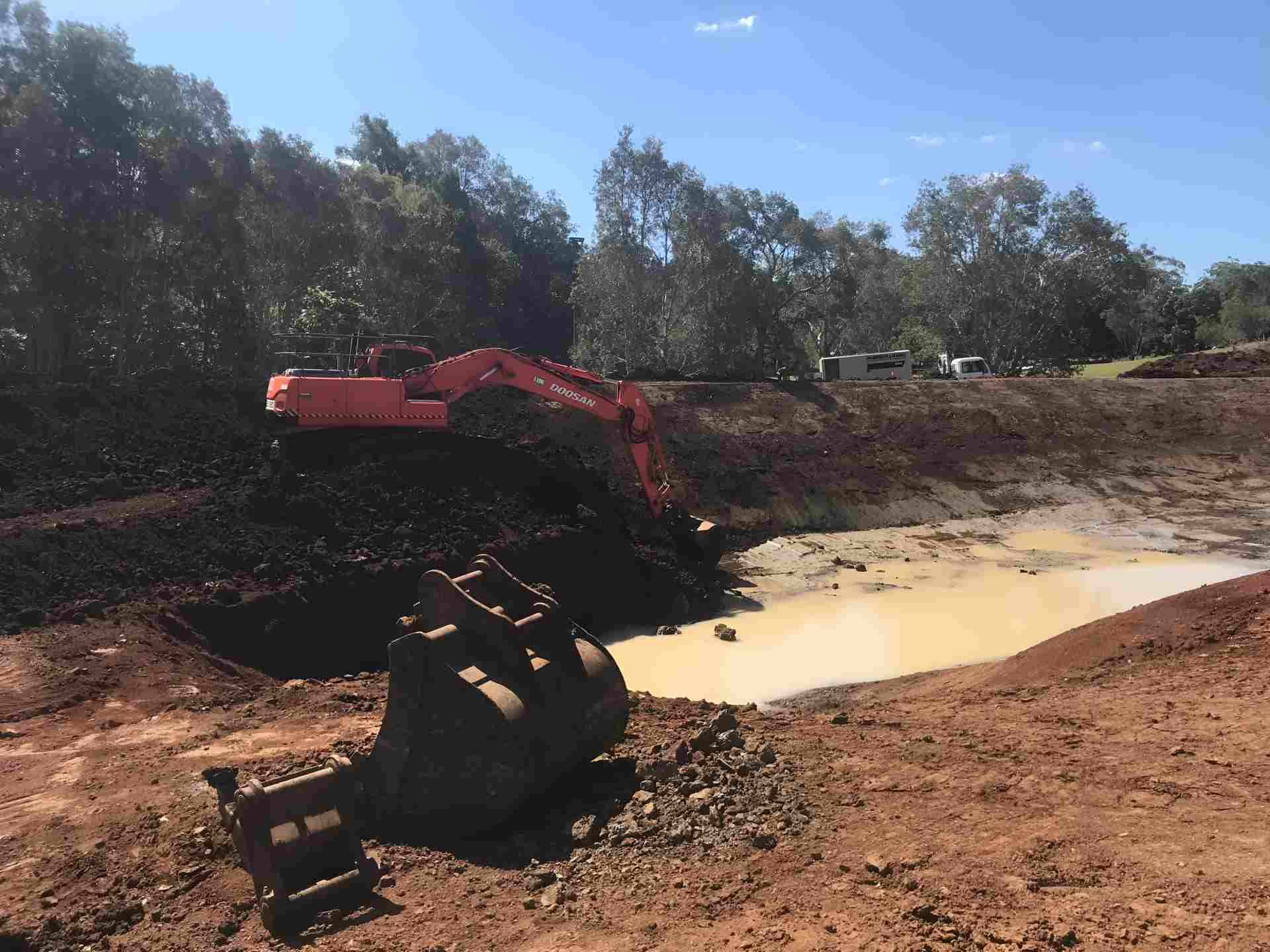 An Excavator is Digging a Hole in the Dirt Near a Pond — Byron Earth & Road in Wardell, NSW