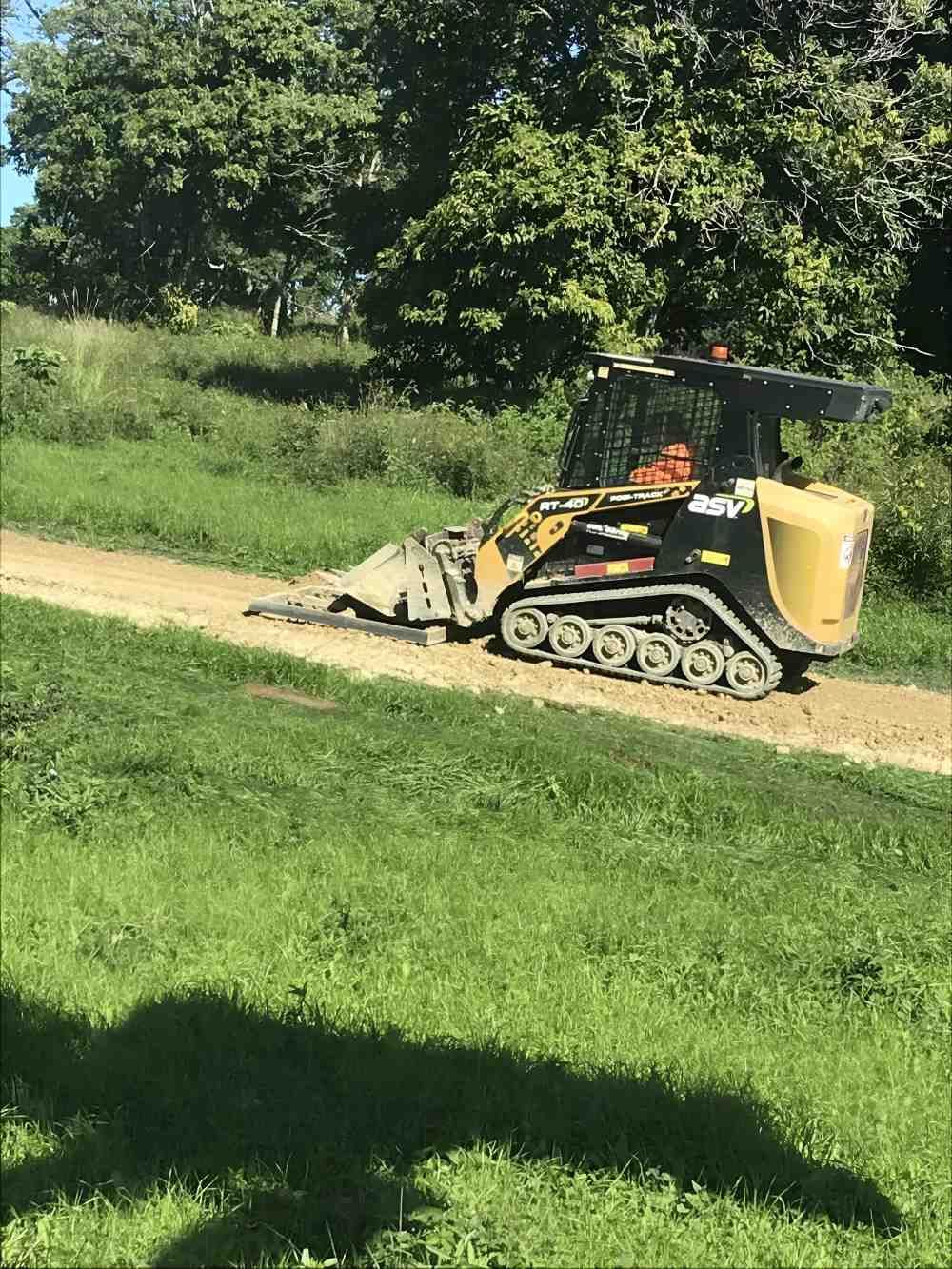 A Bulldozer is Driving Down a Dirt Road Next to a Grassy Field — Byron Earth & Road in Wardell, NSW