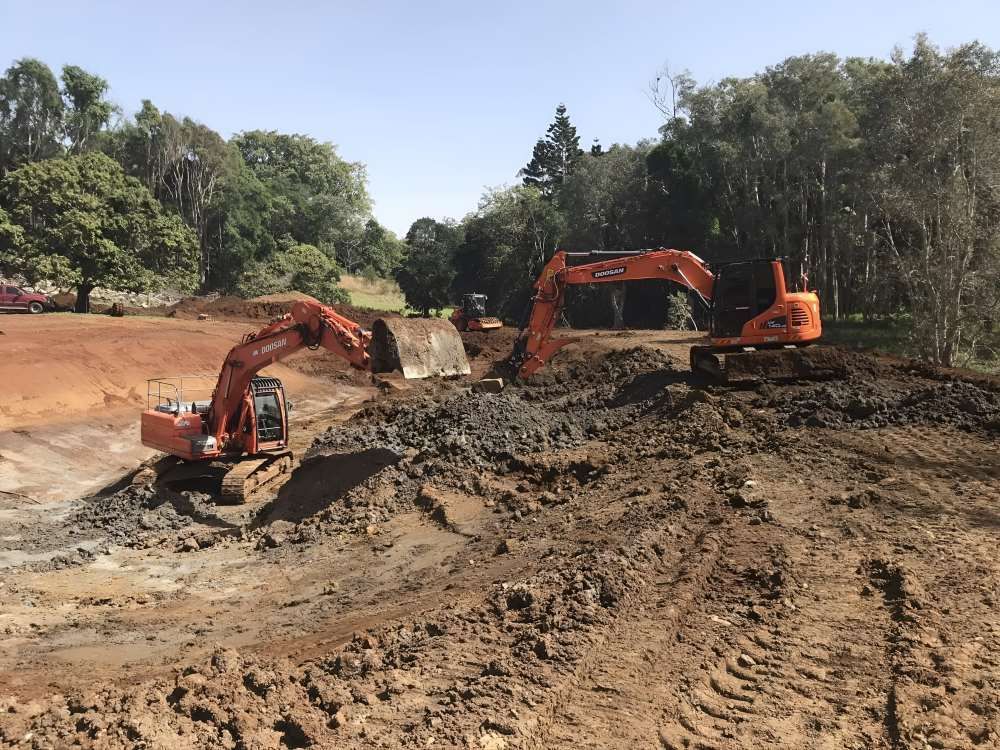 Two Excavators Are Working in a Muddy Field — Byron Earth & Road in Wardell, NSW