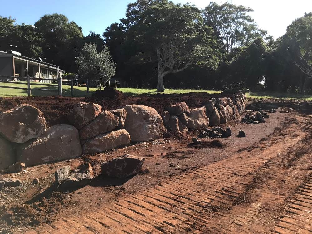 A Large Rock Wall is Being Built in Front of a House — Byron Earth & Road in Wardell, NSW