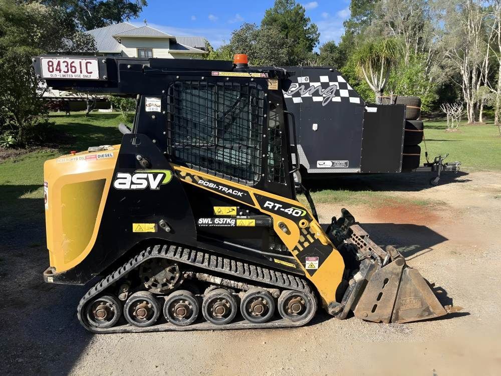 A Bulldozer is Parked in a Driveway Next to a Trailer — Byron Earth & Road in Wardell, NSW