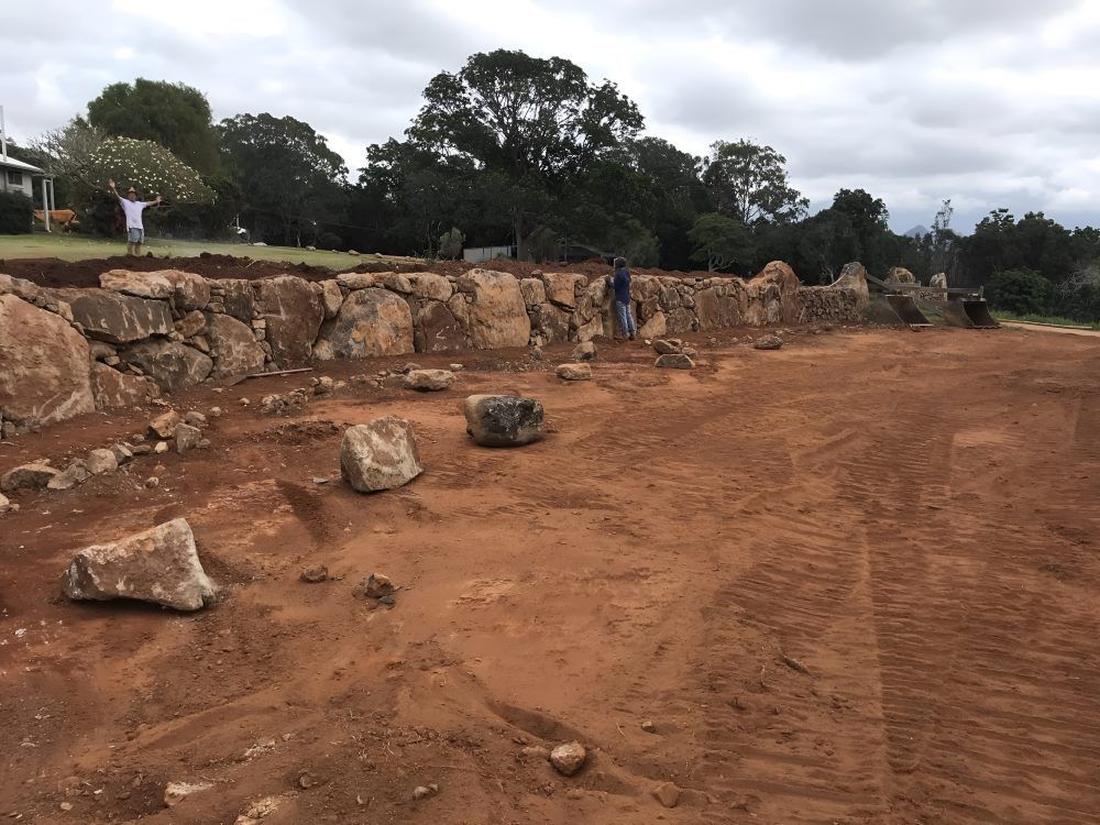 A Large Rock Wall is Being Built in a Dirt Field — Byron Earth & Road in Wardell, NSW