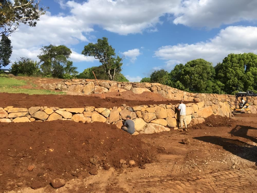 A Group of People Are Working on a Rock Wall in a Field — Byron Earth & Road in Wardell, NSW