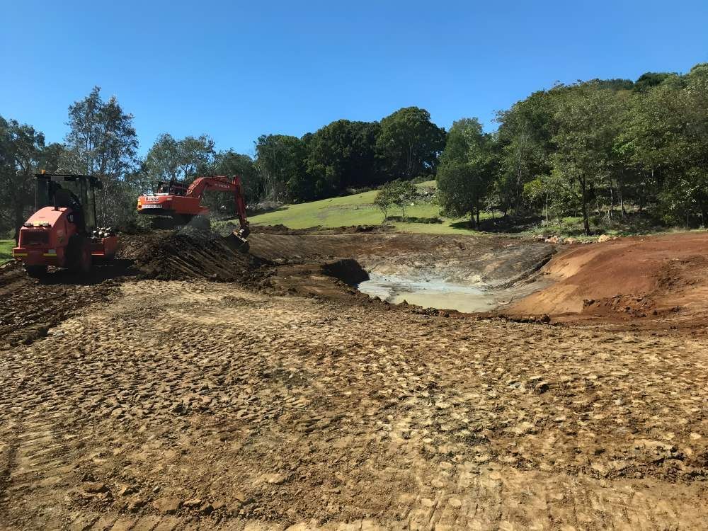 A Large Orange Excavator is Working on a Dirt Field — Byron Earth & Road in Wardell, NSW