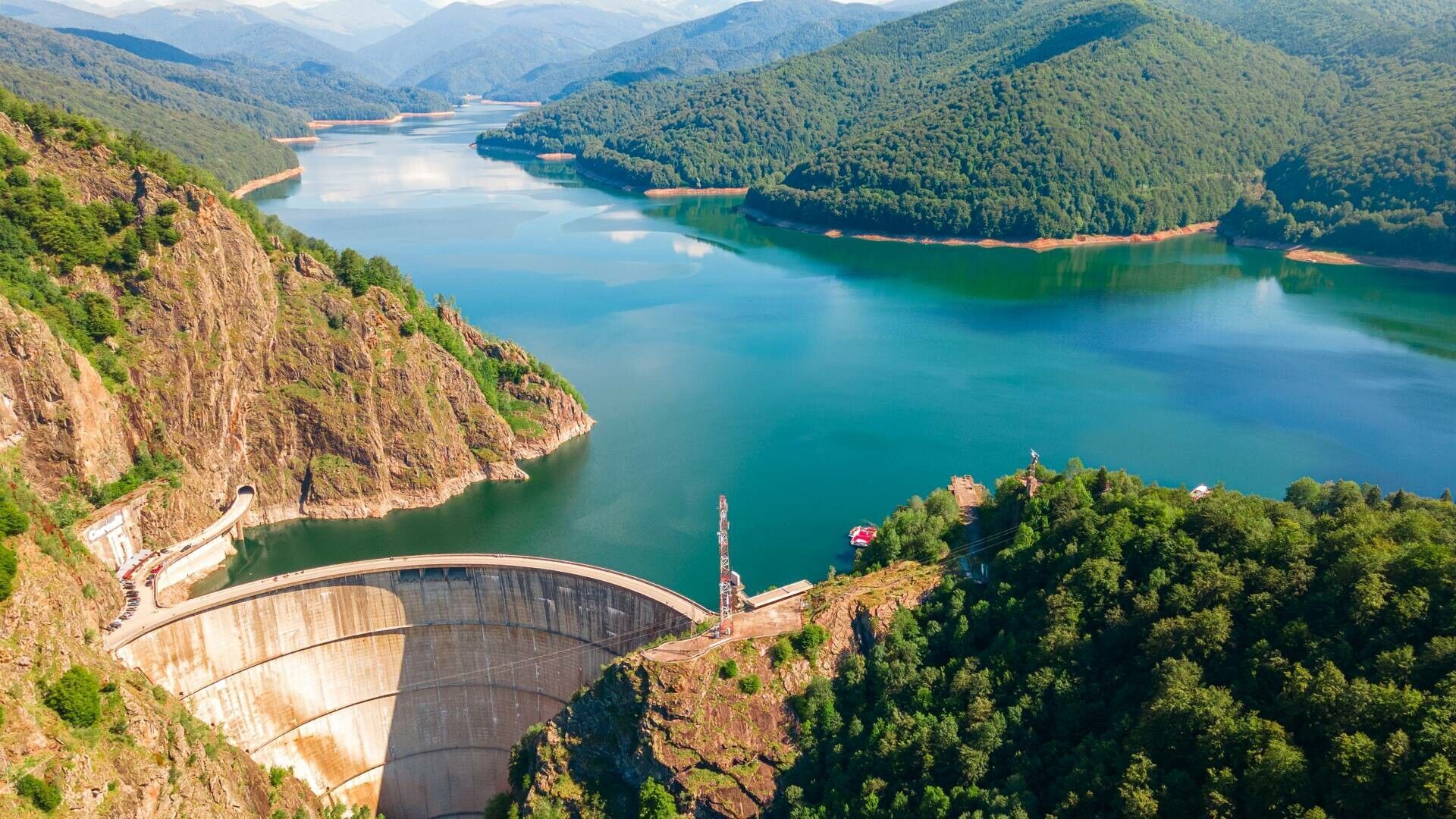 An aerial view of a large lake surrounded by mountains and trees.