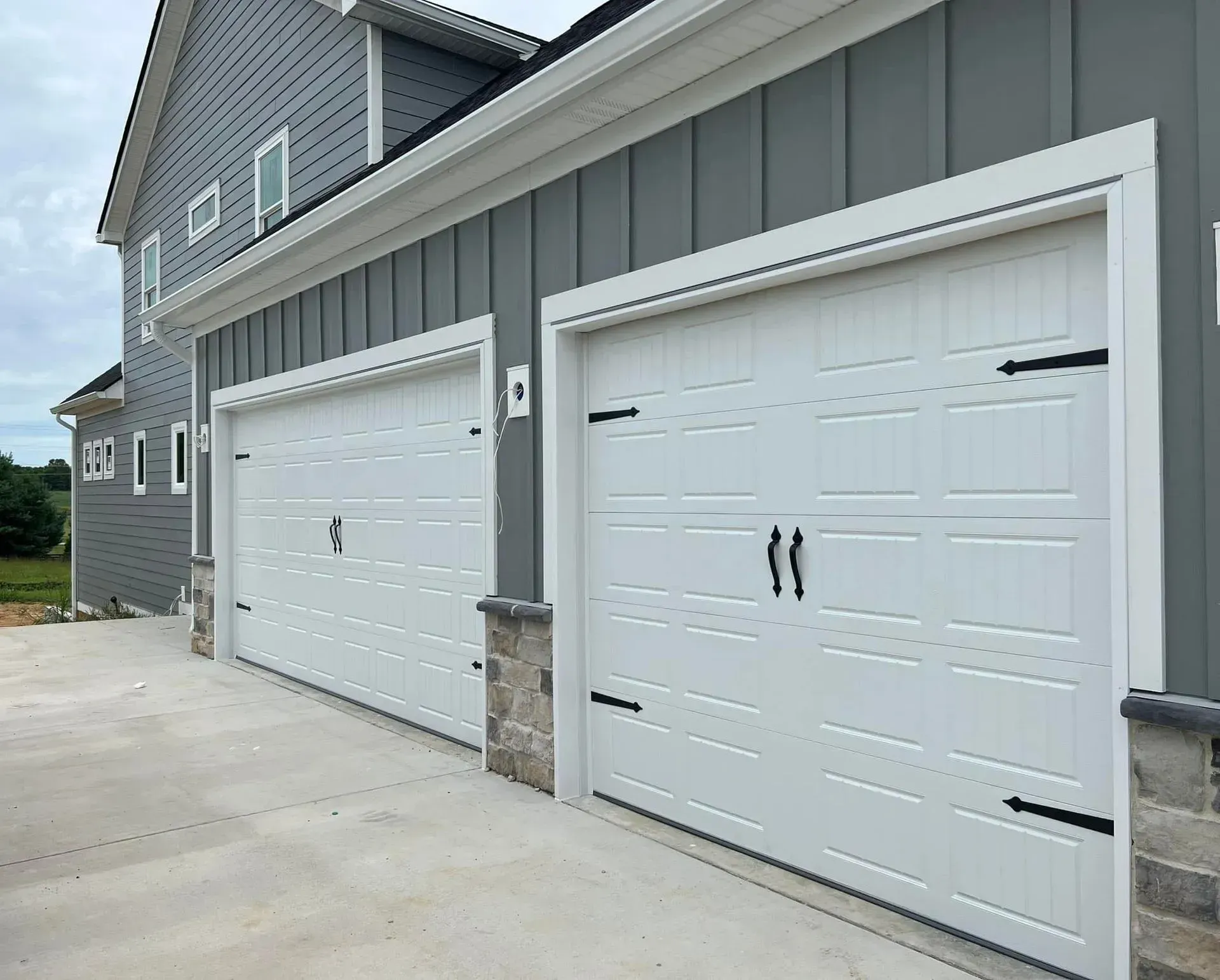 A row of white garage doors on the side of a house.