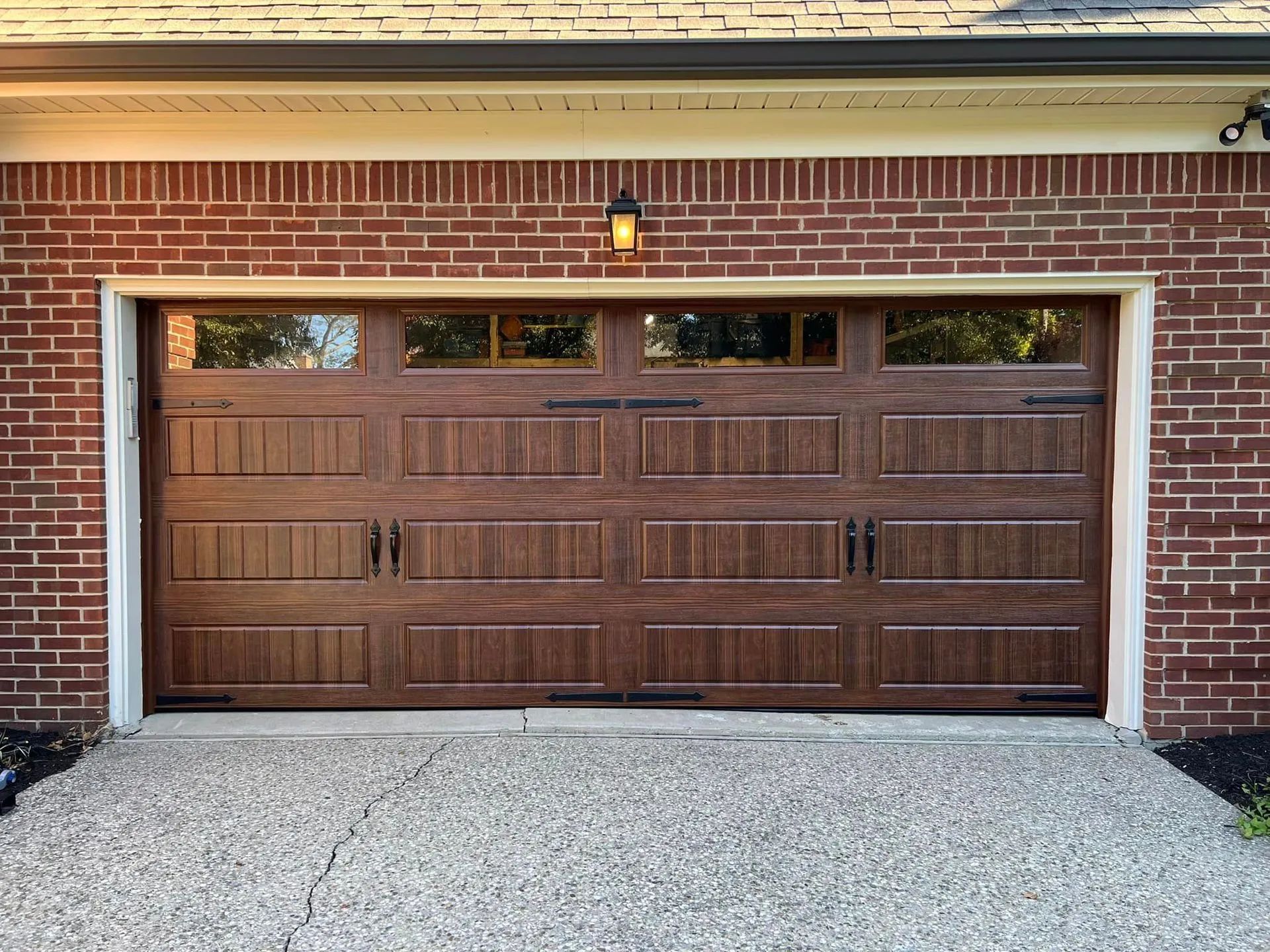 Brown garage door with windows, on a brick building with a concrete driveway.