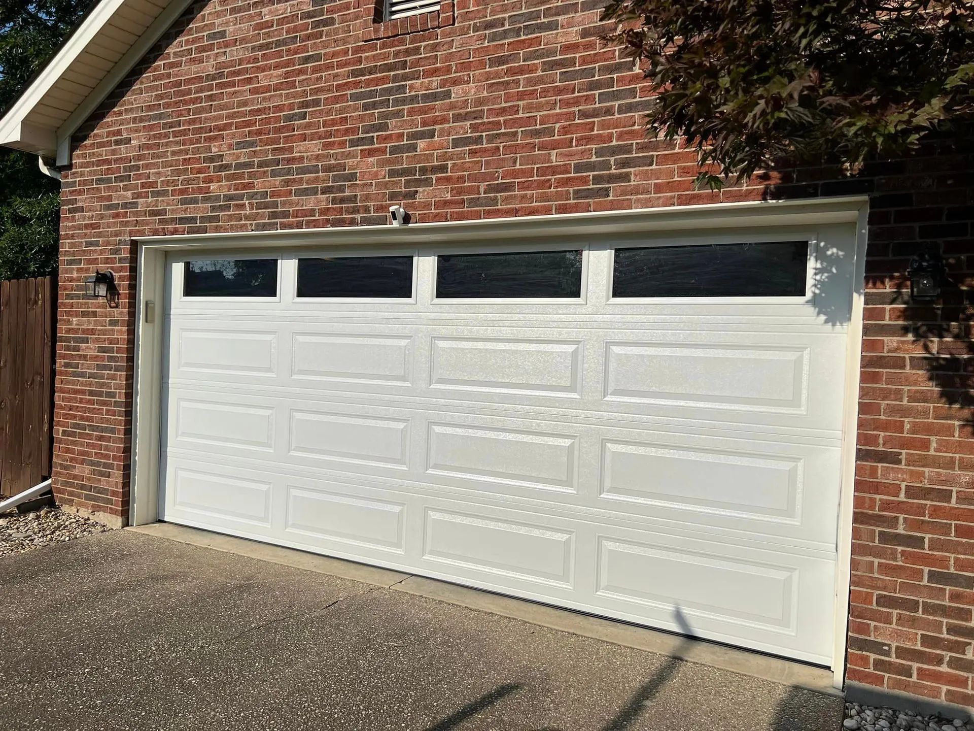 White garage door with windows in a brick building.