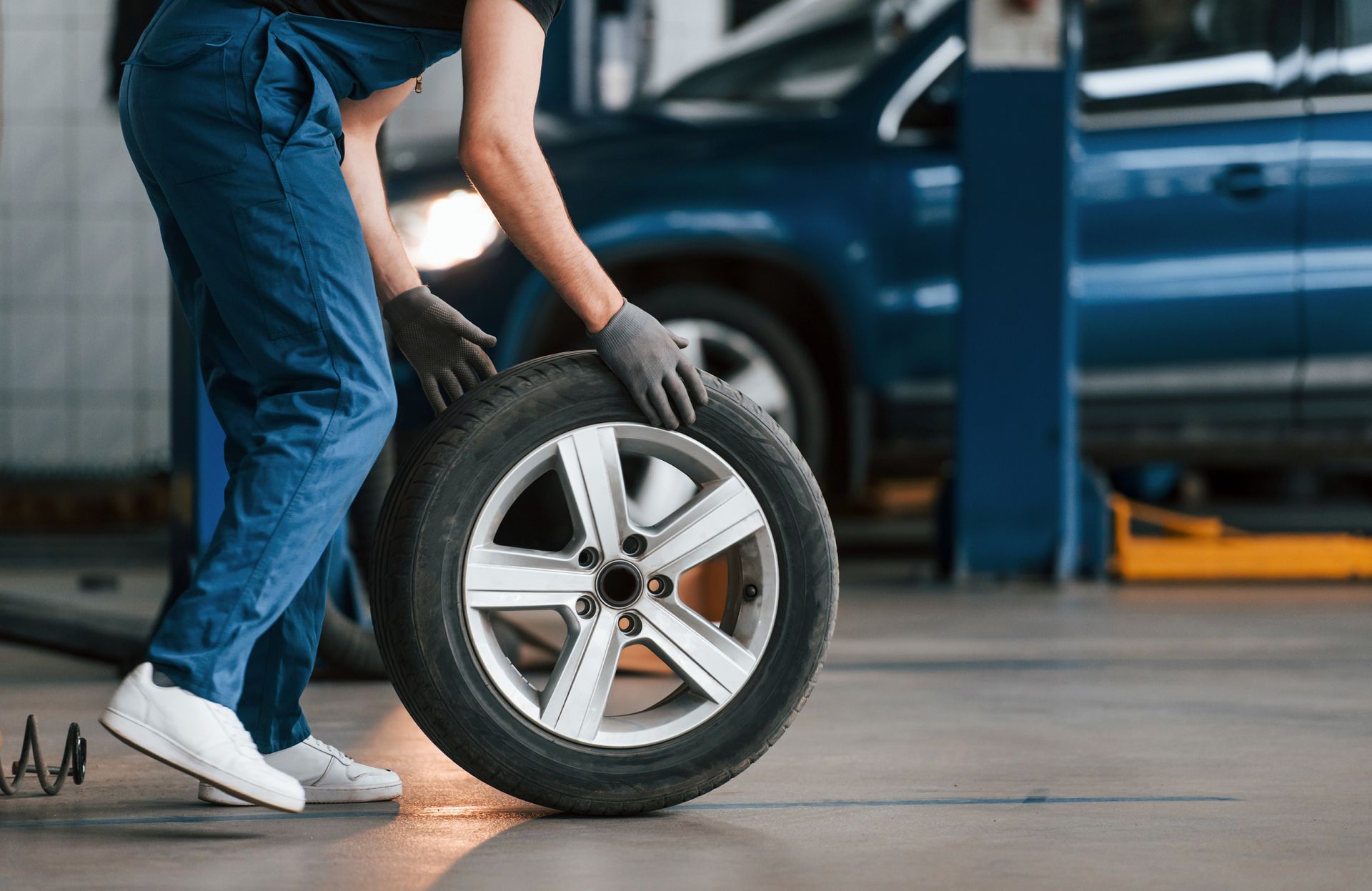 A man is changing a tire in a garage.