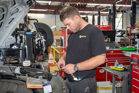 Mechanic inspecting a car engine under the open hood in a garage | Motorvation Service Center