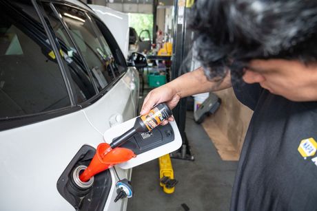 Metal grinding sparks fly in a workshop beside a large orange coil spring. | Motorvation Service Center