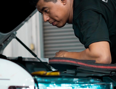 Mechanic inspecting a car engine under the open hood in a garage | Motorvation Service Center