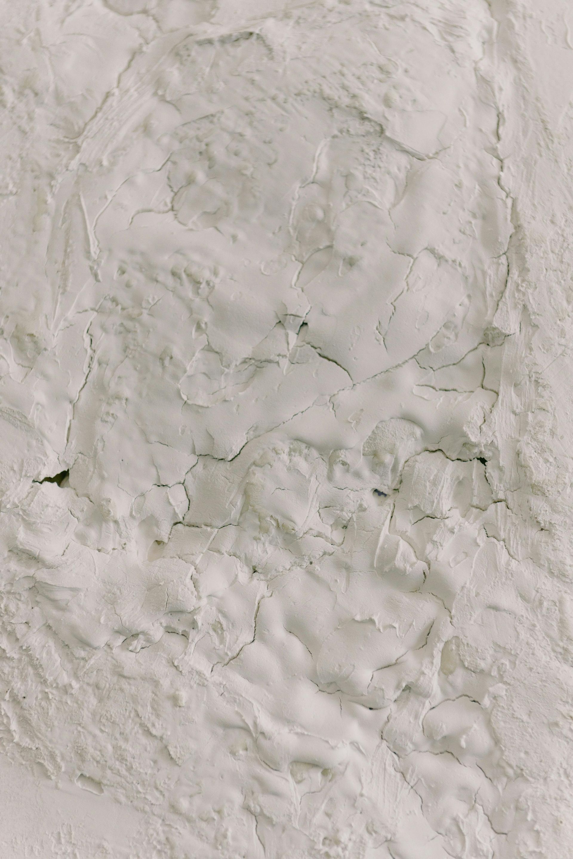 Textured white surface with cracks and uneven patches.