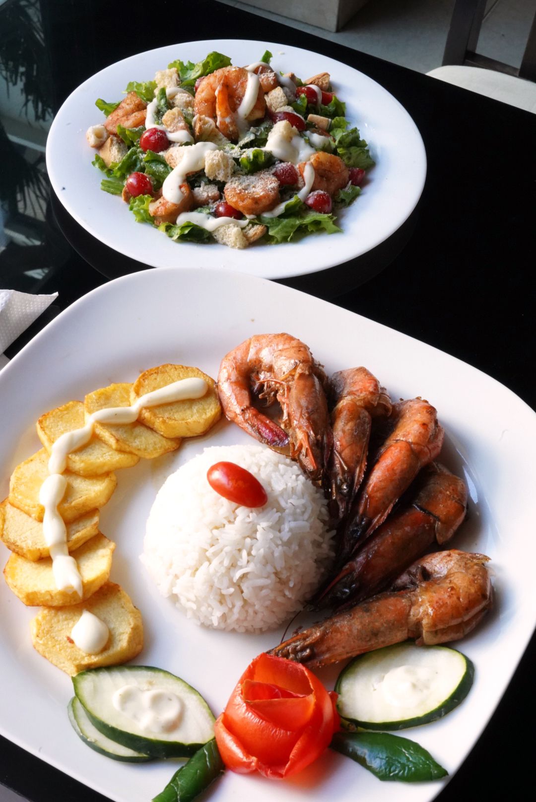 Un plato de comida con camarones, arroz, papas y verduras.