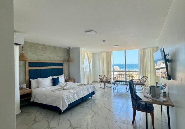 Una habitación de hotel con una cama grande, mesa, sillas y televisión.